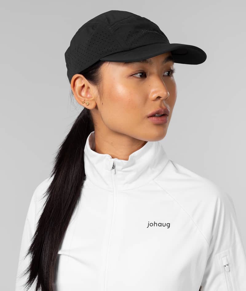 Woman models the lightweight black Johaug Discipline Cap, designed with moisture-wicking fabric for workouts.