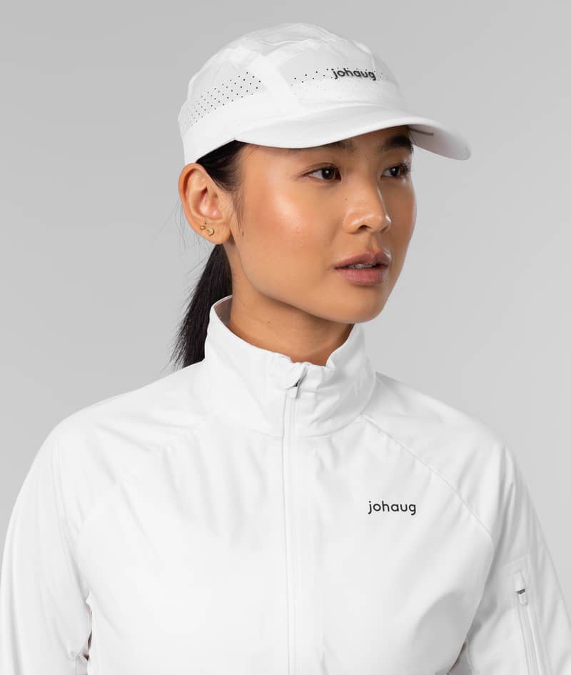 Woman in the white Johaug Discipline Cap, showing the laser-cut ventilation for optimal breathability during training.
