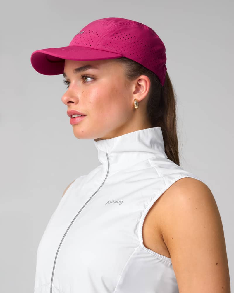 Side profile of a woman in the Johaug berry pink Discipline Cap, showing its breathable design and athletic fit.