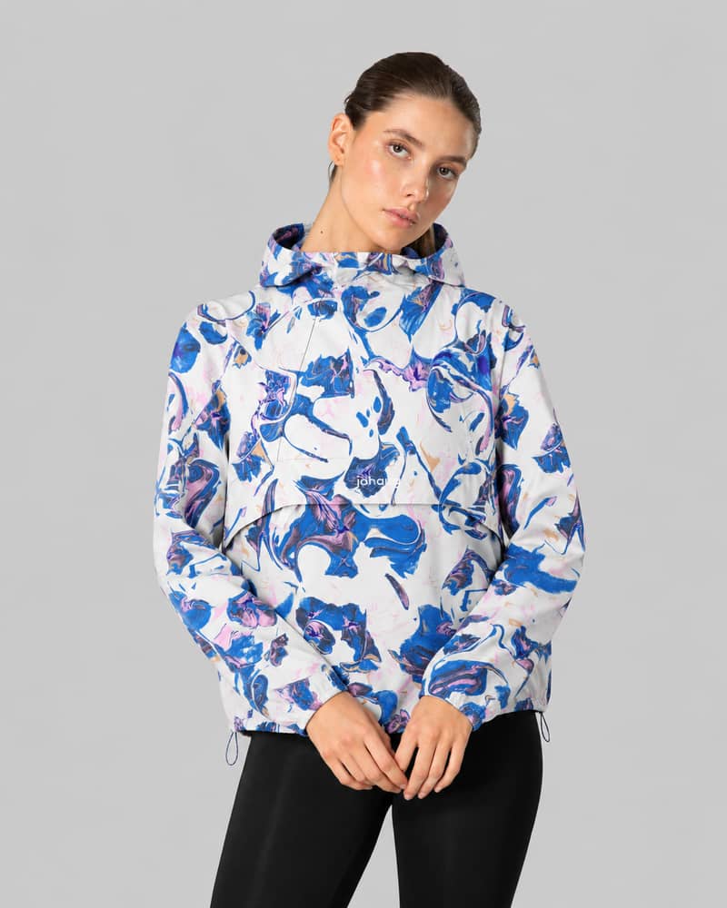 Woman wearing a blue and white floral patterned Johaug anorak pullover jacket, front view, gray background