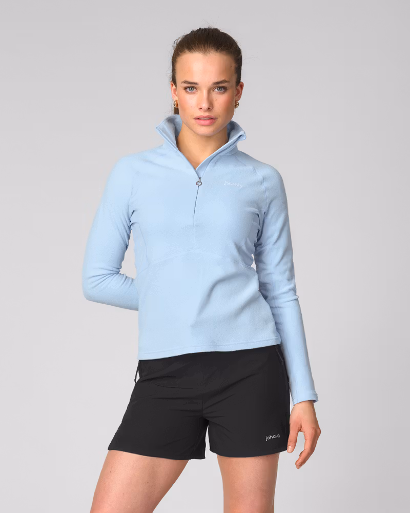 Woman styles the Johaug light blue Fusion Fleece Half Zip, a cosy pullover with a high collar for training or lifestyle.