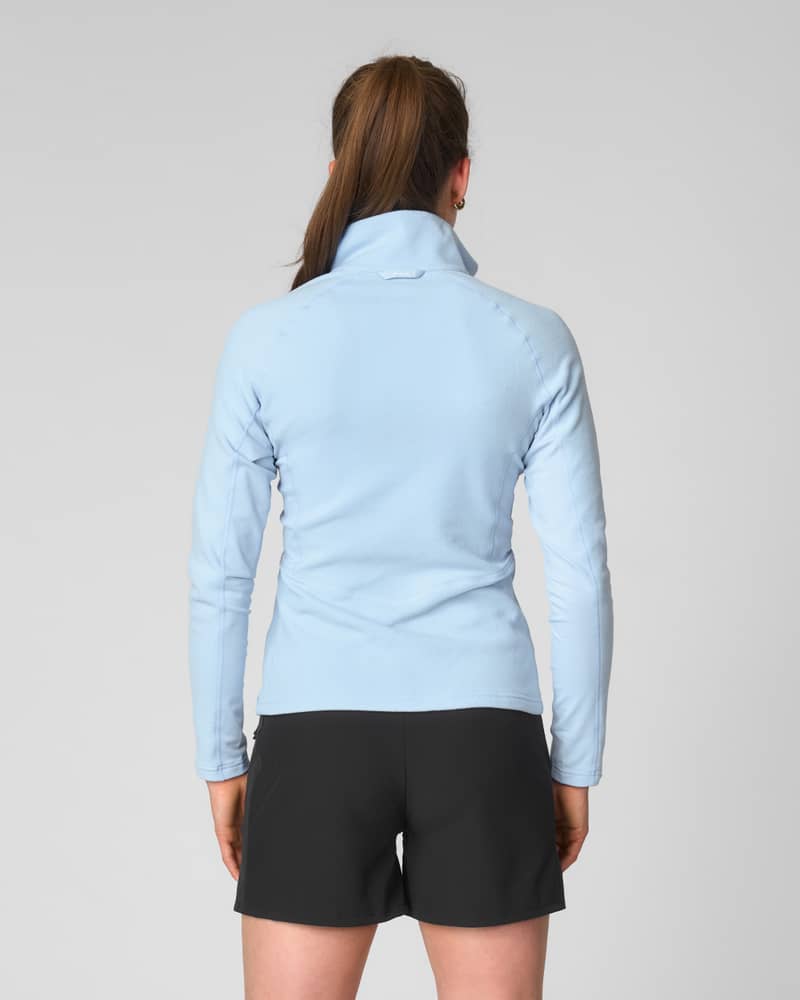 Back view of a woman in the Johaug light blue fleece, showing the extended hem for extra coverage.