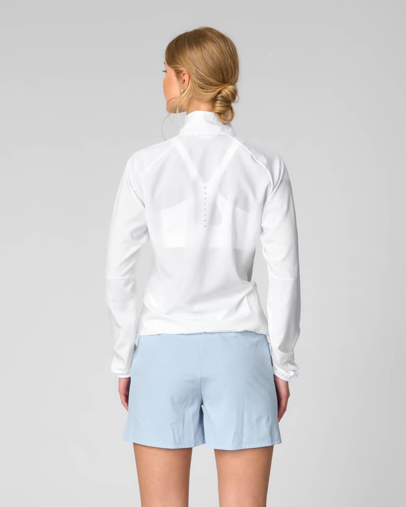 Back view of woman in the white Johaug Energy Training Jacket with reflective logo detail.