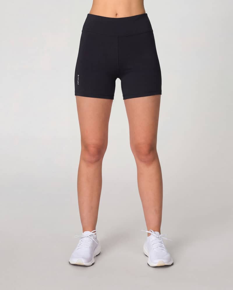Woman wearing black Johaug Energy Tights 5 Inch, showcasing the high-waisted fit of these short training tights for running.