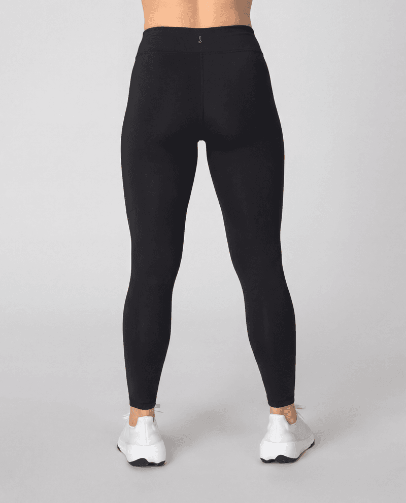Back view of a woman wearing black Johaug Energy Tights, highlighting the slim fit and supportive wide waistband.