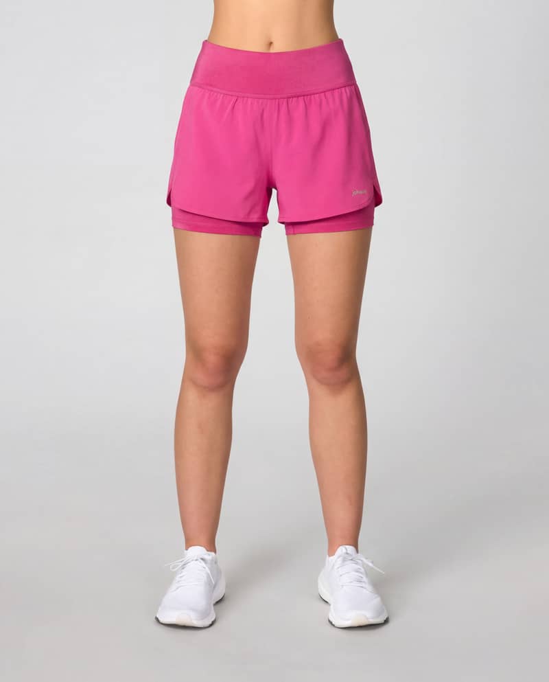 Woman wearing Johaug berry pink Impact 2 in 1 Shorts with black inner shorts for running.