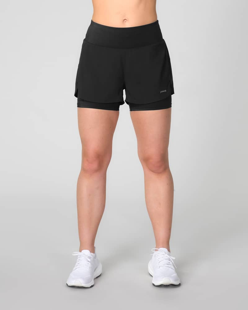 Woman wearing Johaug black Impact 2 in 1 running shorts, showing the high-waisted, supportive fit.