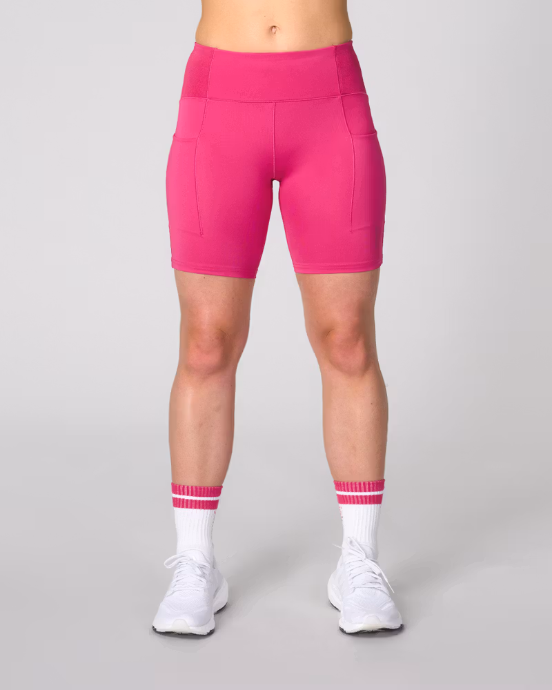 Woman wearing Johaug berry pink Impact Biker Tights, styled for a high-intensity workout.