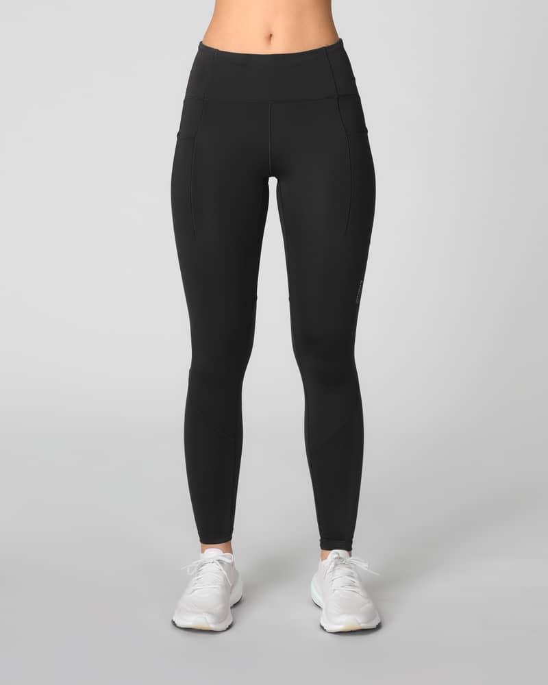 Woman wearing Johaug black Impact running tights, showcasing the high-waisted, supportive fit for training.