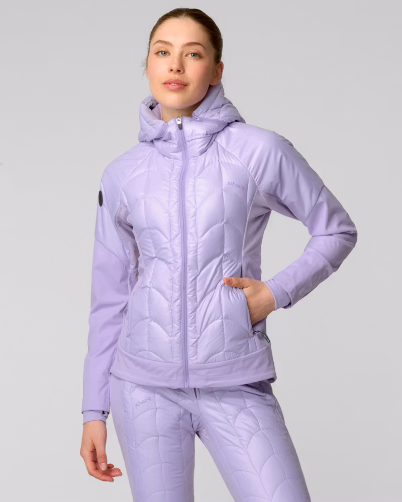 Woman wearing a lavender quilted ski jacket with hood, holding ski poles outdoors