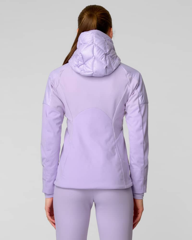 Close-up of woman wearing a lavender quilted puffer jacket with hood in falling snow