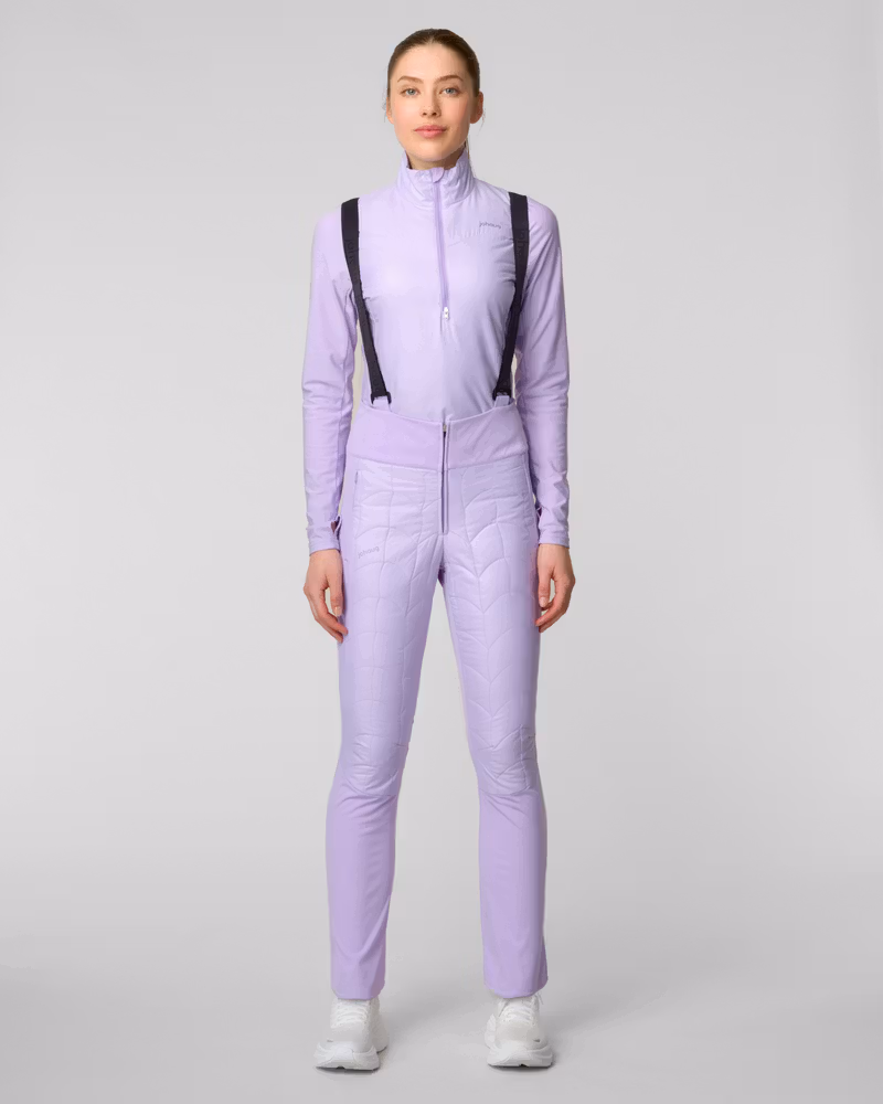 Woman wearing lavender high-waisted ski pants with suspender straps, side view