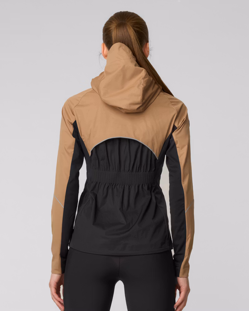 Woman running in a camel and black colorblock hooded jacket with logo detail